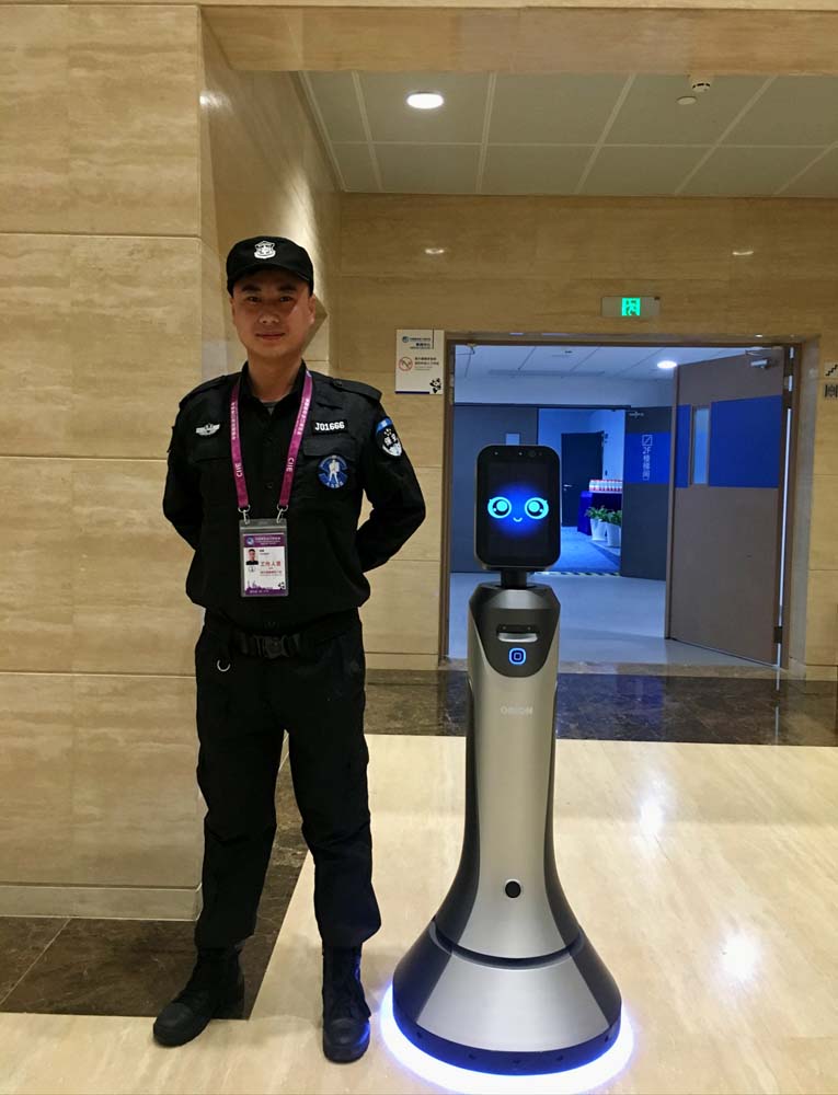 图片默认标题_fororder_首届中国国际进口博览会上的场馆保安与智能机器人向导豹小秘 摄影：王竹