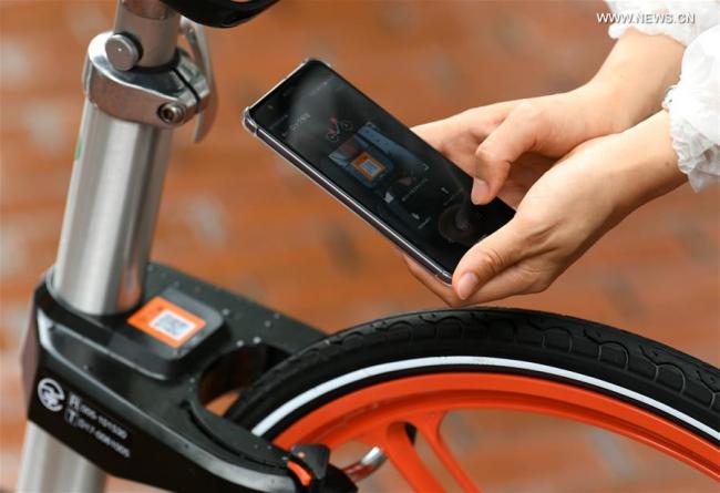 A woman uses her cellphone to unlock a shared bicycle in Sapporo, Japan, on Aug. 22, 2017. [Photo: Xinhua/Hua Yi]