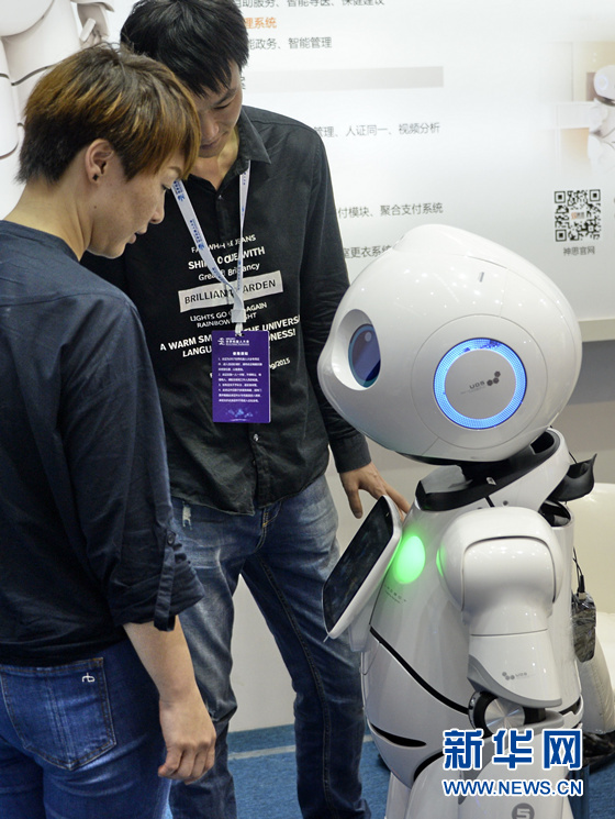 A staff member is explaining the functions of the robot to a visitor. [Photo: from Xinhua] 
