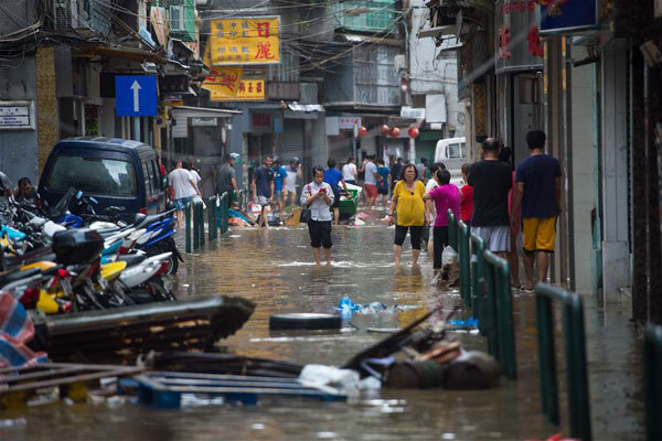 Residents wade through a water-logged road in Macao, south China, Aug. 23, 2017. Hato, the 13th typhoon to hit China this year, made landfall in the city of Zhuhai in southern China's Guangdong Province at noon Wednesday. Affected by Hato, Macao has canceled all marine transport and most of airlines. [Photo: Xinhua]