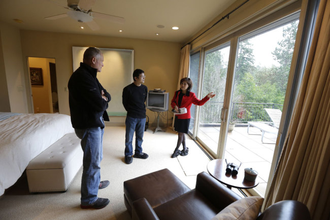 Janie Lee, right, a residential specialist with John L. Scott Real Estate, shows a home for sale to her client, Hongbin Wei, center, of Beijing, China, Thursday, Dec. 18, 2014, in Medina, Wash., near Seattle, as homeowner Doug Ebstyne looks on at left.[Photo: AP]