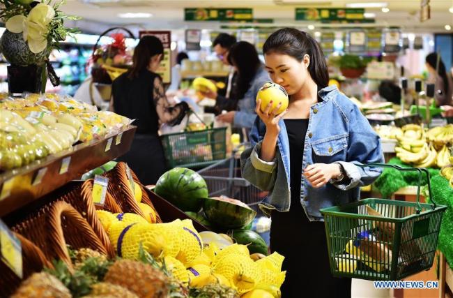 A woman selects melon at a supermarket in Shijiazhuang, Hebei Province. [File photo: Xinhua]