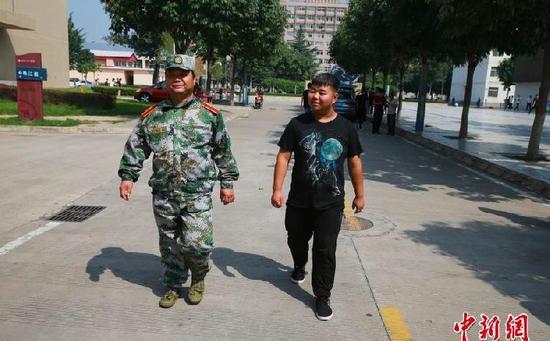 44-year-old Sun Xinke (left) walks with his son Sun Yingkang at their Yangling Vocational & Technical College in northwest China's Shaanxi Province. [Photo: Chinanews.com]