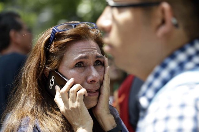 A woman tries to reach people on her cellphone after she evacuated with others to Paseo de la Reforma Avenue after an earthquake in Mexico City, Tuesday, Sept. 19, 2017. A powerful earthquake jolted central Mexico on Tuesday, causing buildings to sway sickeningly in the capital on the anniversary of a 1985 quake that did major damage. [Photo: AP]
