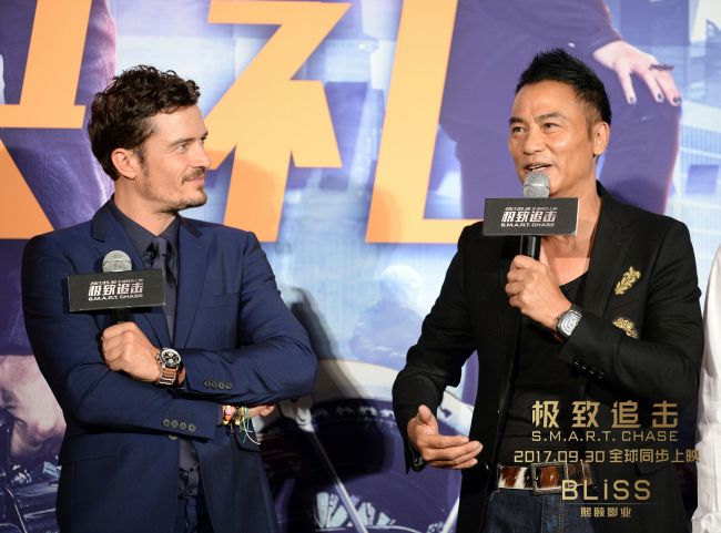 English actor Orlando Bloom (left) looks at Simon Yam, who's speaking at the premiere of their upcoming action-packed thriller film 'Smart Chase.' [Photo: China Plus]