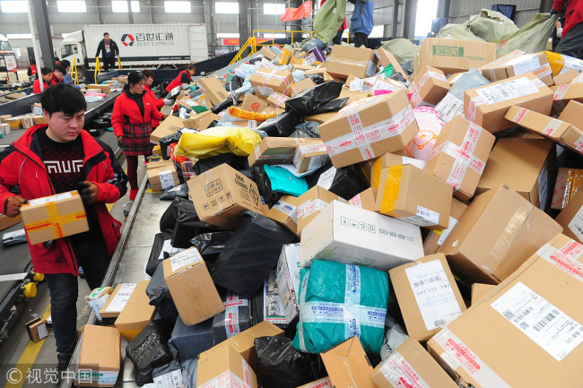 Staff members sort packages at an express delivery company. [File photo: VCG]