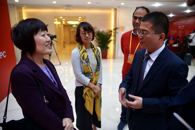 Wang Dongmei, Secretary of the Secretariat of All-China Journalists Association, chats with Xia Yongmin at the press center of the 19th CPC National Congress in Beijing on Friday, Oct. 20, 2017. [Photo: China Plus]