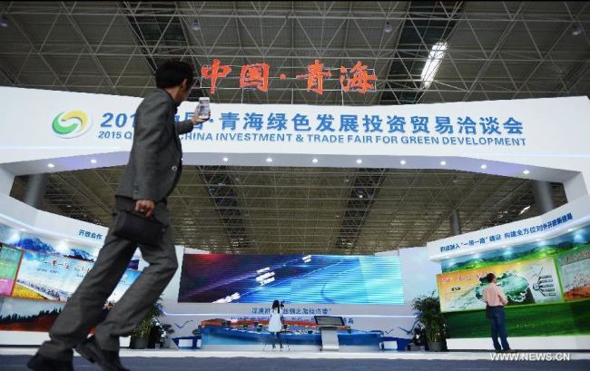A man takes pictures of an exhibition booth at 2015 Qinghai China Investment & Trade Fair for Green Development in Xining, captal of northwest China's Qinghai Province, June 17, 2015. The four-day fair kicked off here Tuesday. [Photo: Xinhua]