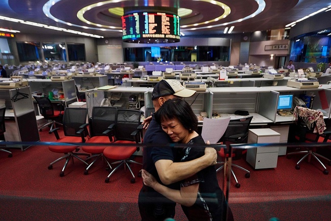 In this picture taken on October 19, 2017, Cheng (R), a trader who has worked on the floor since 1994, hugs a colleague as she prepares to leave on her last day of work at the Hong Kong Stock Exchange. [Photo: VCG/Focus/Elaine Yu]