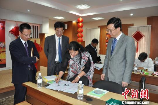 A government official (2nd, right) from Nepal's Ministry of Foreign Affairs practices Chinese calligraphy in Kathmandu, 0n June 9, 2014. [File Photo: Chinanews.com]