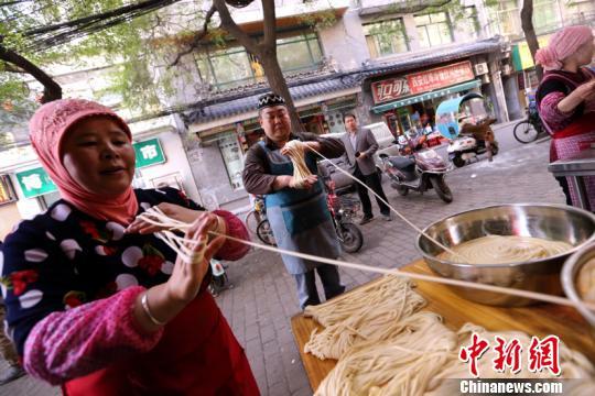 Lan Jianbo and his employee pulling noodles in Xi’an, northwest China’s Shaanxi Province, on November 2, 2017. [Photo: Chinanews.com]