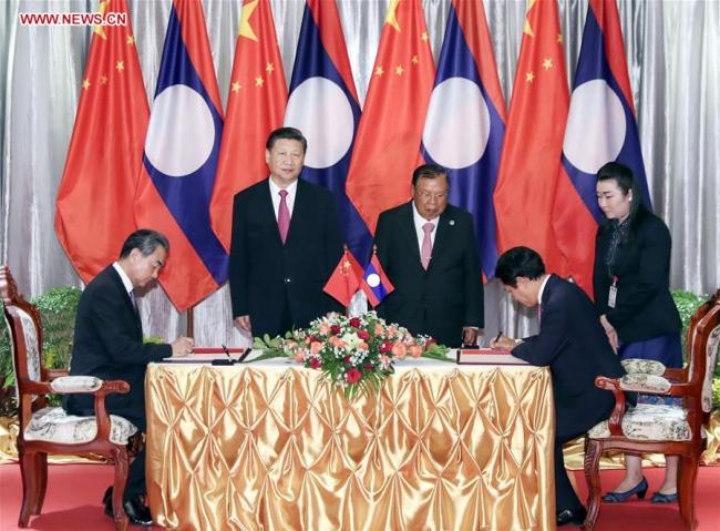 Chinese President Xi Jinping (L rear), also general secretary of the Communist Party of China Central Committee, and Lao President Bounnhang Vorachit (C rear), also general secretary of the Lao People's Revolutionary Party Central Committee, witness the signing of a deal to enhance cooperation under new circumstances between the two countries after meeting again in Vientiane, Laos, Nov. 14, 2017. [Photo: Xinhua]