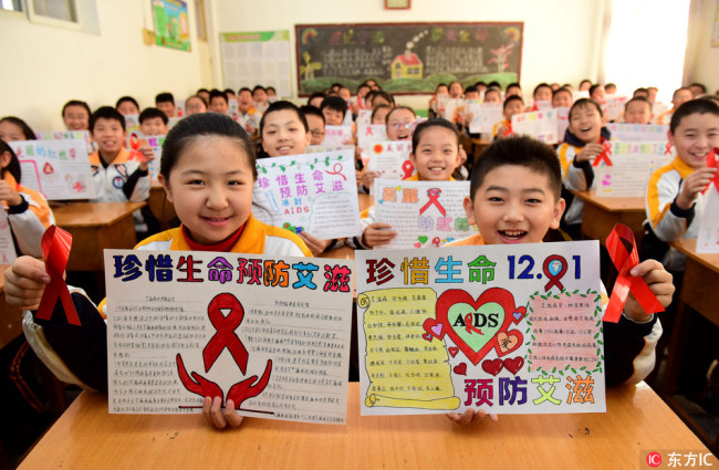 Students from a primary school in Shijiazhuang, Hebei Province demonstrate the creative pictures and red ribbons to promote AIDS prevention on November 30, 2017. [Photo: IC]