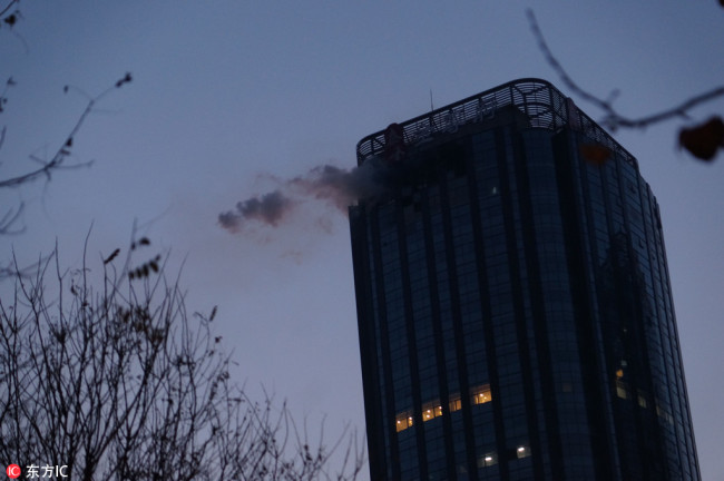 Smoke rises from the upper floors of Tianjin City Tower during the fire which killed ten residents in Tianjin, December 1, 2017. [Photo: IC]