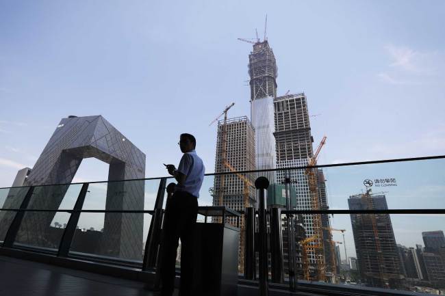A man stands at a balcony of a newly opened shopping mall against the China's state broadcaster China Central Television (CCTV) headquarters and construction buildings in Beijing, Thursday, June 15, 2017. [File photo: AP]