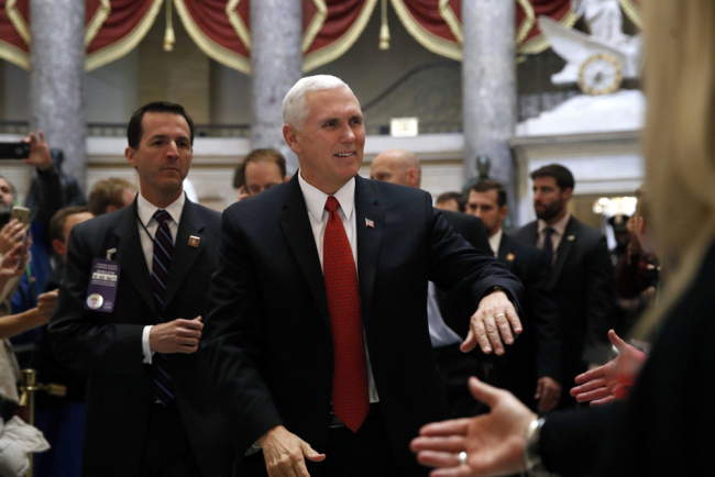 U.S. Vice President Mike Pence greets people as he walks to the House Chamber during voting on the Republican tax bill, Tuesday, Dec. 19, 2017, on Capitol Hill in Washington. [Photo: AP/Jacquelyn Martin]