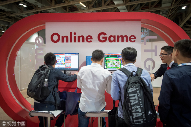 Attendees look at online games made by LT Game Ltd., a subsidiary of Paradise Entertainment Ltd., during the Macau Gaming Show (MGS) in Macau, China, Nov. 14, 2017. Macau regulators are strengthening their oversight of the almost $30 billion casino industry as they plan to release details next year of the renewal process for operators. [Photo: VCG] 