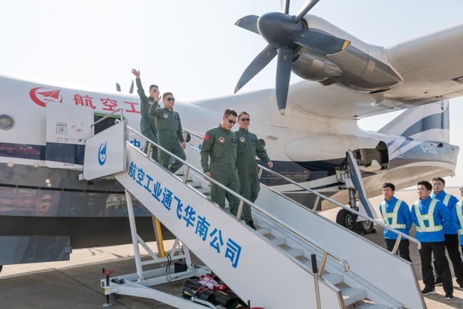 The crew members wave after China's first domestic large amphibious aircraft AG600 completed its maiden flight and landed at the Jinwan Civil Aviation Airport in the city of Zhuhai, Guangdong Province, on Sunday, December 24, 2017. [Photo: China Plus/Li Jin]
