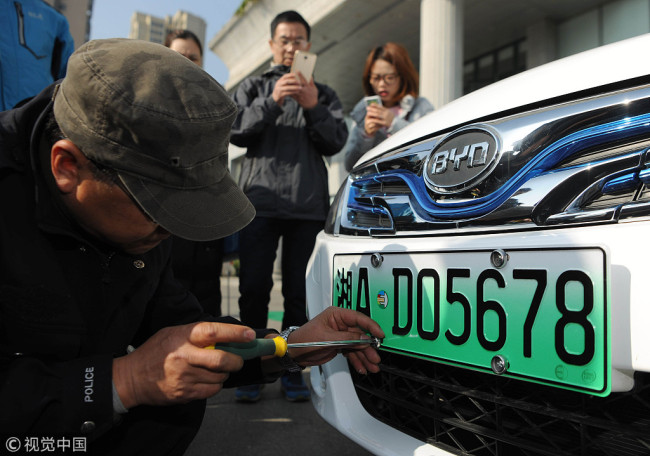 A person accepts a vehicle plate designed especially for new energy vehicles in Changsha, Hunan Province on December 25, 2017. [Photo: VCG]