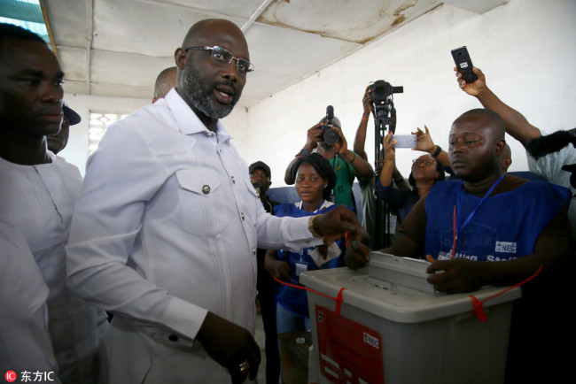 Liberian presidential candidate for the Coalition for Democratic Change (CDC), George Weah (C) casts his ballot in presidential elections run-off in Monrovia, Liberia, 26 December 2017. Some 2.1 million registered Liberian voters are eligible to vote in the presidential run-off between George Weah, of the Coalition for Democratic Change (CDC), and Joseph Nyuma Boakai of the governing Unity Party (UP). [Photo: IC/EPA/Ahmed Jallanzo]