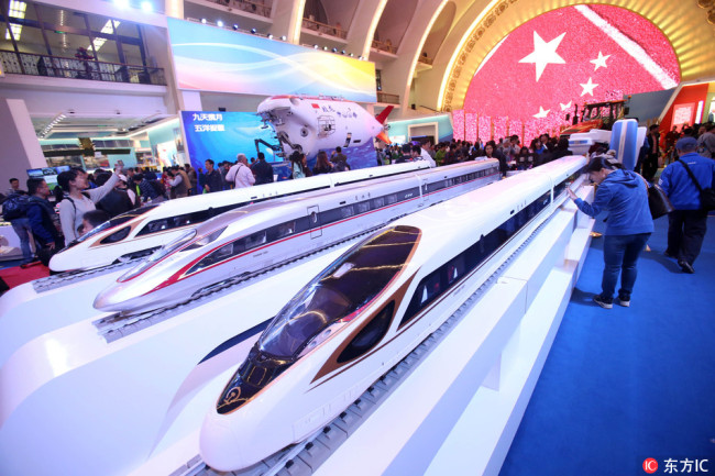 Visitors look at models of bullet trains during an exhibition in Beijing, China, October 7, 2017. [File Photo: IC]