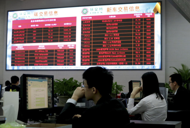 In this May 12, 2015 photo, workers monitor the carbon trading at the Beijing Environmental Exchange office in Beijing, China.[Photo: AP/Andy Wong]