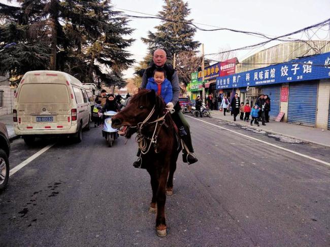 A father and son ride a horse on a street in Xianyang, northwest China's Shaanxi Province on January 12, 2018. [Photo: Sanqin Metropolis Daily]