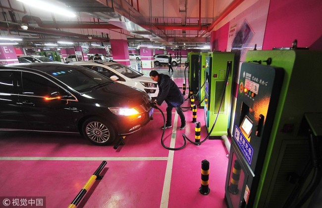 A man charges his new energy car at an underground parking lot in Beijing on December 28, 2017. [File photo: VCG]