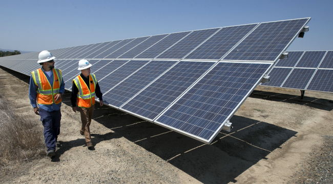 Solar Tech Joshua Valdez, left, and Senior Plant Manager Tim Wisdom walk past solar panels and at a Pacific Gas and Electric Solar Plant, Thursday, Aug. 17, 2017, in Vacaville, Calif. [Photo: AP]