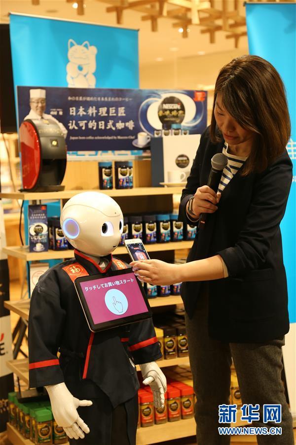 One of the café's human employees shows a customer how to pay a robot using Alipay. [Photo: Xinhua]