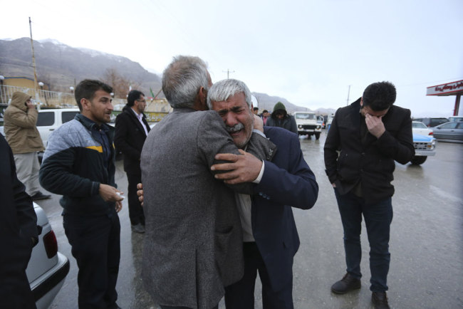 In this photo provided by Tasnim News Agency, family members of a plane crash victims weep in the village of Bideh, at the area that the plane crashed, southern Iran, Sunday, Feb. 18, 2018. An Iranian commercial plane crashed Sunday in a foggy, mountainous region of southern Iran, and officials said they feared all people aboard were killed. [Photo: Ali Khodaei/Tasnim News Agency via AP]