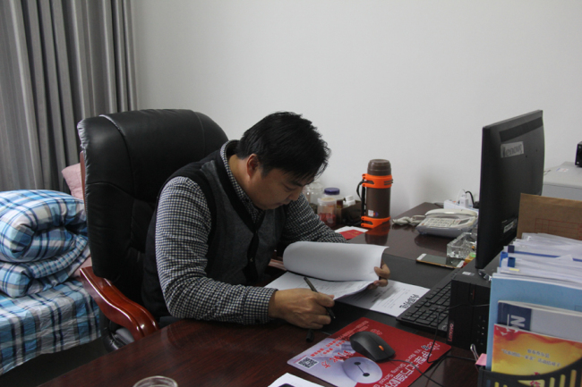 Zhou Yuanli, head of Qapqal poverty relief office reads reports on November 18th in his office in Qabqal county government. [Photo: China Plus/Yang Guang]
