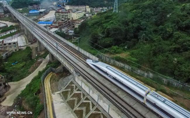 The high-speed train G3002 runs past the Guiding section on a newly-opened rail line in Guiding County, southwest China's Guizhou Province, June 18, 2015.[Photo: Xinhua]