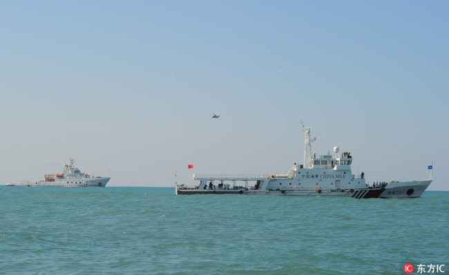 A helicopter flies over rescue vessels during a drill jointly conducted by the Ministry of Transport's Nanhai Rescue Bureau, Nanhai No 1 Flying Rescue Service and the Hainan Maritime Safety Administration in Sanya city, south China's Hainan province, on December 19, 2017. [File Photo: IC]