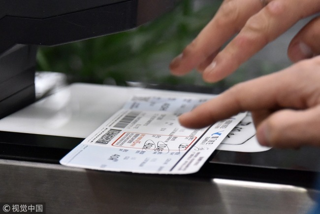 A passenger puts a boarding pass through an ID check at Beijing Capital International Airport, April 4, 2018. [Photo: VCG]