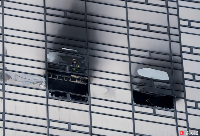 A firefighter looks out from the window of a fire damaged apartment in Trump Tower in New York on Saturday, April 7, 2018. The Fire Department says the blaze broke out on the 50th floor shortly before 6 p.m. Saturday. [Photo: IC]