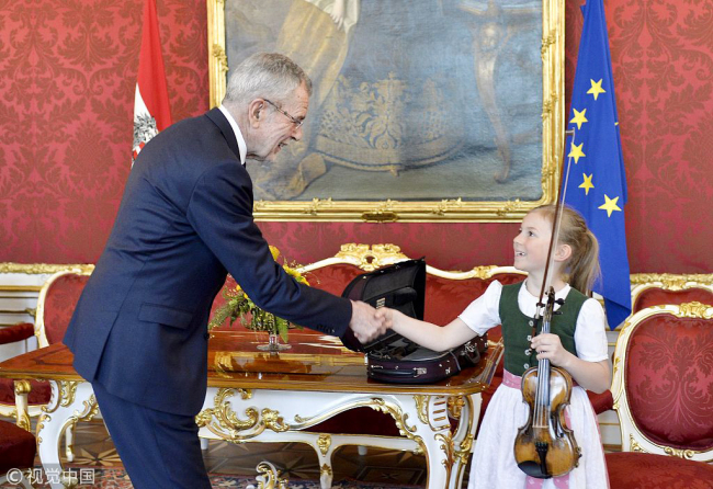 Anna Cacilia Pfoess shakes hands with Austrian President Alexander Van der Bellen after playing a violin used by Mozart at the Chancellery in Vienna, Austria, Friday, April 6, 2018. [Photo: VCG]