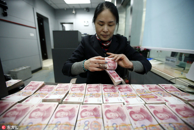 A clerk counts RMB (renminbi) banknotes at a bank in Huaibei city, Anhui Province, January 22, 2015. [File Photo: IC]