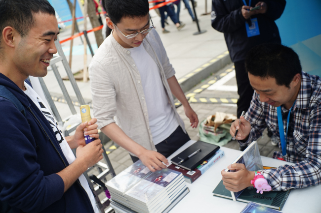 Chinese writer Moxiong signs autographs for his readers on May 20,2018.[Photo:CRI] 
