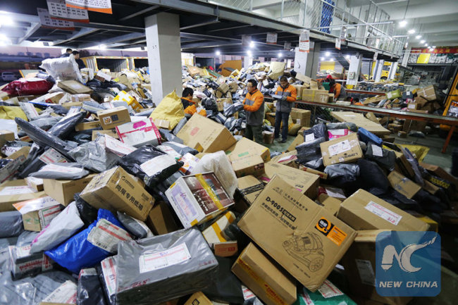 File photo taken on Nov. 13, 2014 shows couriers sorting parcels at an express facility in Weifang, east China's Shandong Province. [File Photo: Xinhua]