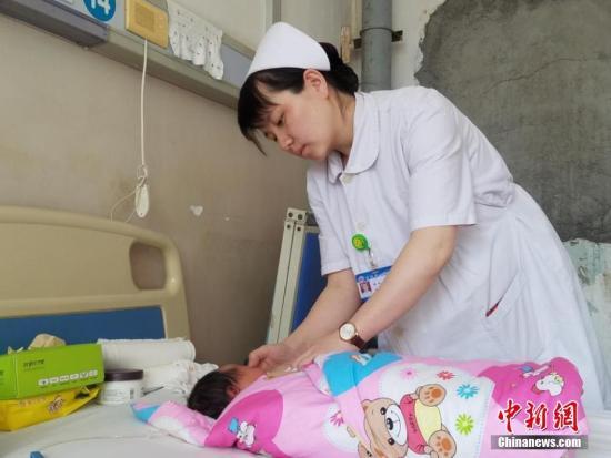 A pediatric nurse cares for a child in a pediatric ward. [Photo: Chinanews.com]