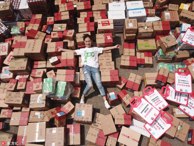 Peng poses with 618 delivery parcels of food, clothing, and daily necessities she received in Nanjing, capital of East China's Jiangsu Province, June 18, 2018. [Photo/IC]