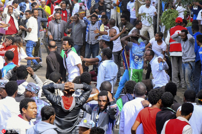 An injured man is helped by others as security officers gather at the scene of an explosion during a massive rally to support Ethiopia's new Prime Minister Abiy Ahmed in Meskel Square in Addis Ababa on June 23, 2018. [Photo: EPA]
