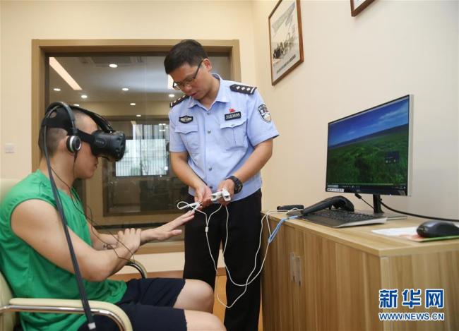 A police officer helps a patient wearing VR devices on June 20, 2018, at Shanghai Qingdong rehabilitation center. [Photo: Xinhua]