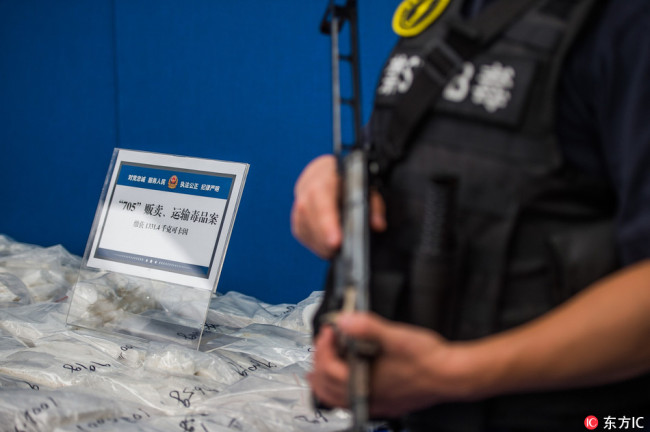 An armed police officer stands guard next to drugs seized by police on display at a press conference in Shenzhen city, Guangdong province, 26 June 2018. [File photo: IC]