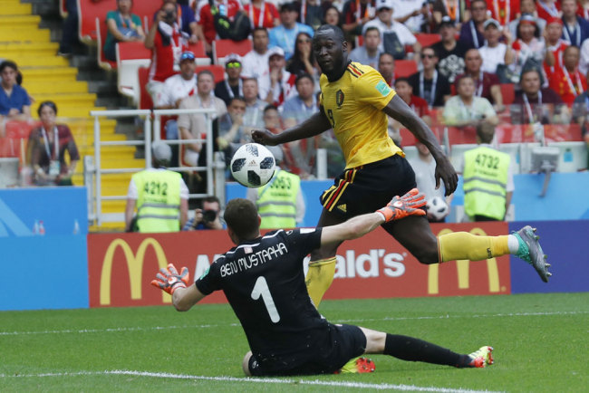 Belgium's Romelu Lukaku , right, scores his side's third goal past Tunisia goalkeeper Farouk Ben Mustapha during a Group G match between Belgium and Tunisia at the 2018 soccer World Cup at Spartak Stadium in Moscow, Russia, Saturday, June 23, 2018. [Photo: AP/Hassan Ammar]