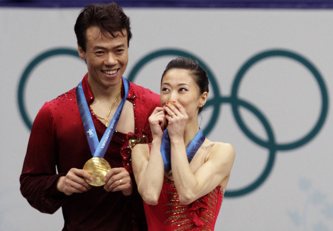 China's Shen Xue, right, kisses her gold medal as Zhao Hongbo, left, looks on, after they won the pairs free program figure skating competition at the Vancouver 2010 Olympics in Vancouver, British Columbia, Monday, Feb. 15, 2010.[Photo:AP]