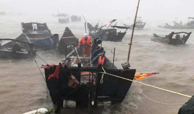 Firefighters use a boat to evacuate a stranded fisherman off Lianjiang county of Fujian province's capital, Fuzhou, on Wednesday. [China Daily]