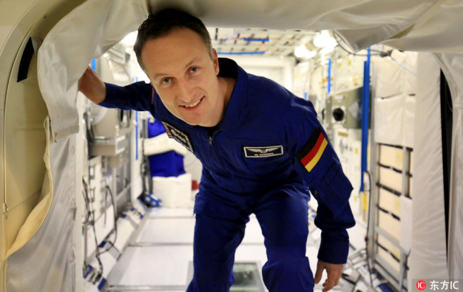 Astronaut Matthias Maurer at a training center for the European Space Agency, stands next to a model of a space capsule. [File photo:IC]