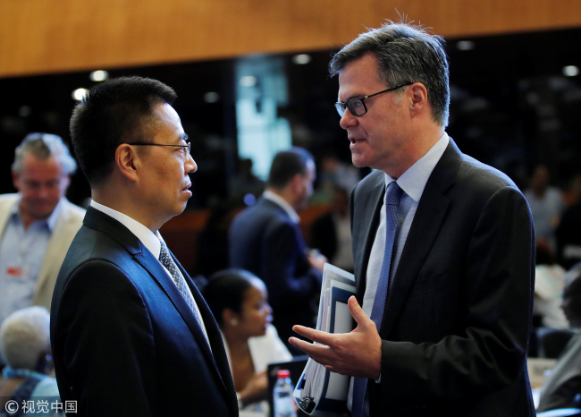 US ambassador to the WTO,  Dennis Shea, talks with Chinese ambassador to the WTO,  Xiangchen Zhang, before the General meeting at the WTO, Switzerland, July 26, 2018. [File Photo:VCG]
